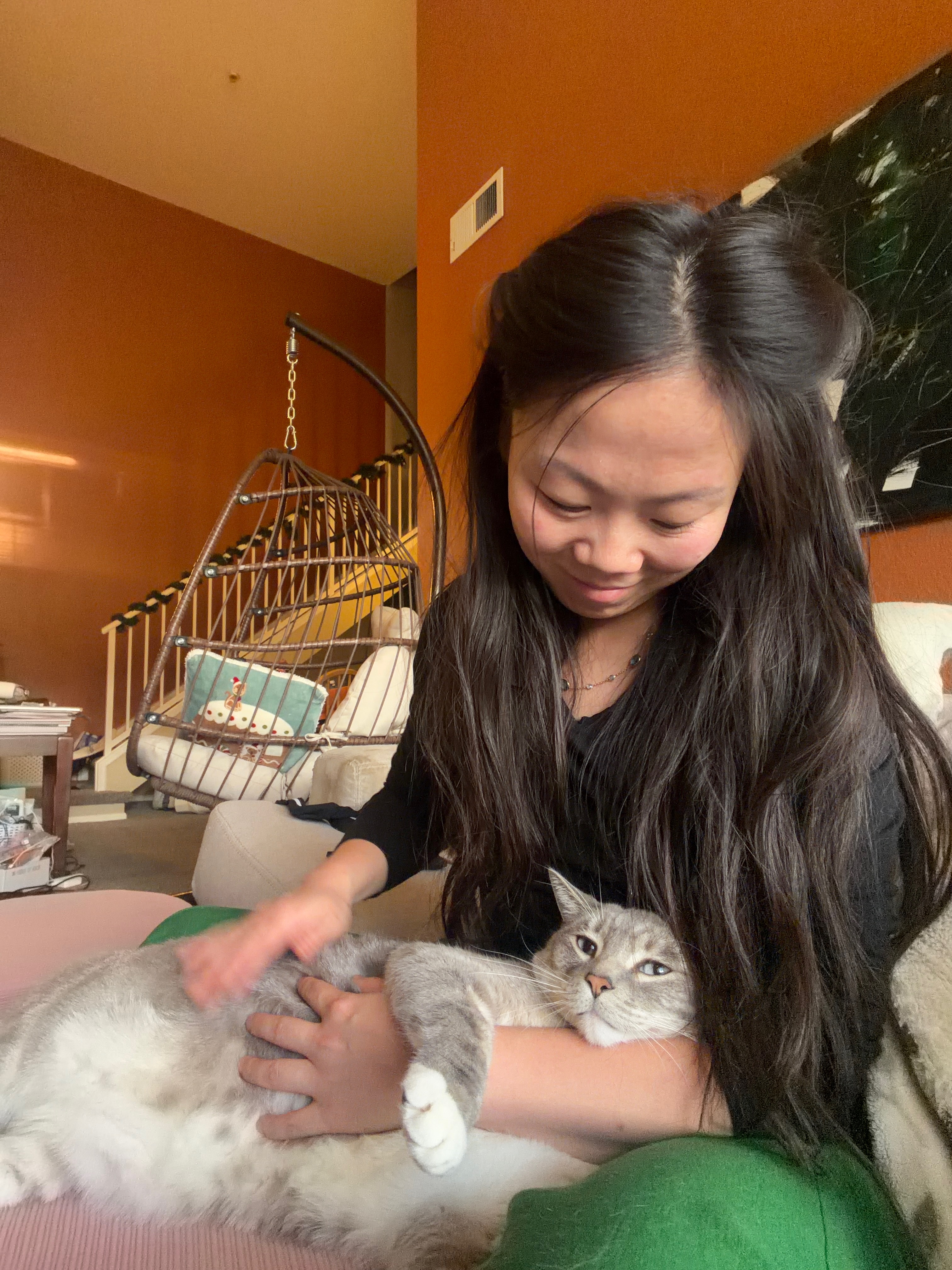 Mama smiling down at the gray tabby cuddled in her lap